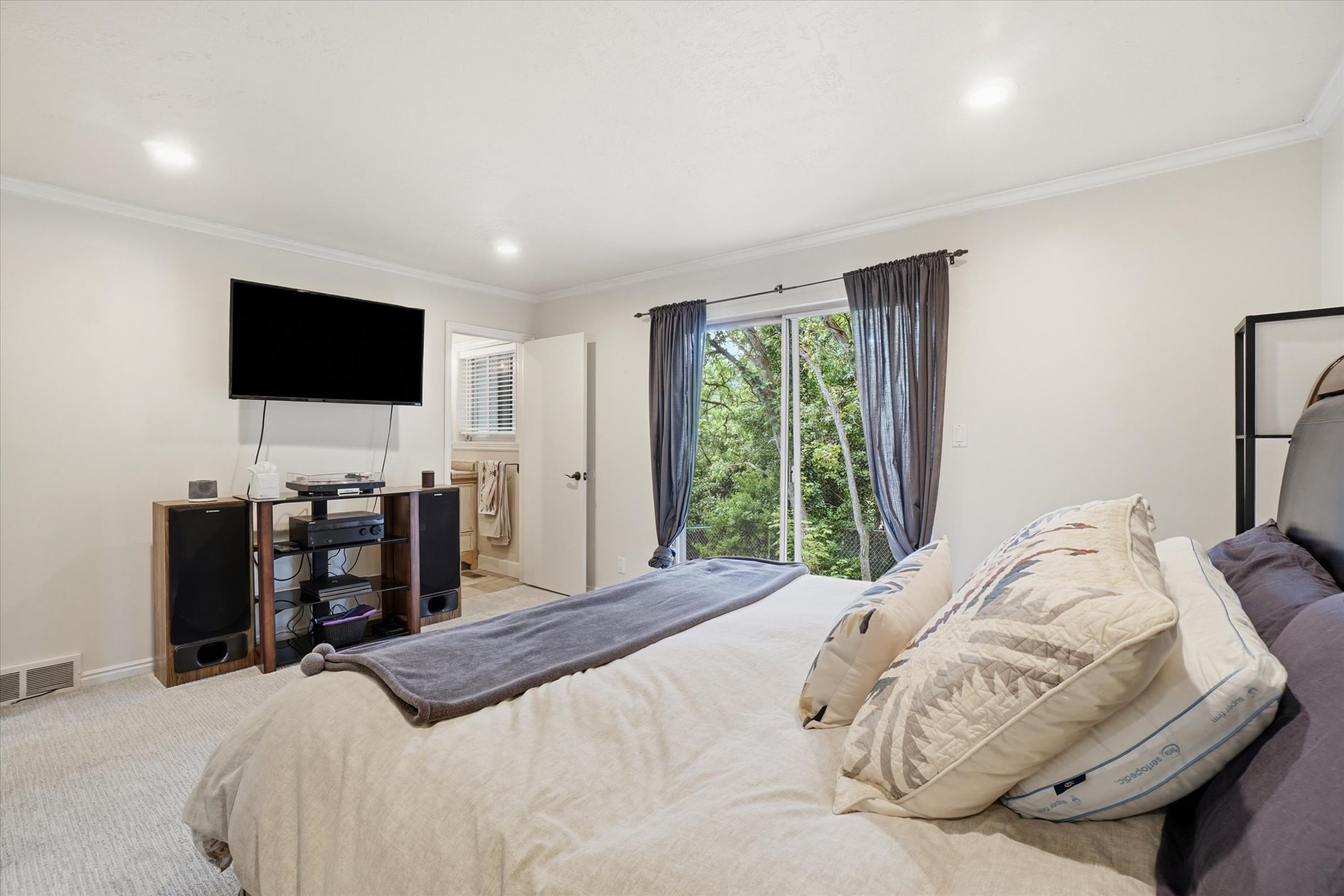 Light-filled bedroom featuring recessed lighting, crown molding, light-toned carpeting, and sliding glass door access to exterior greenery