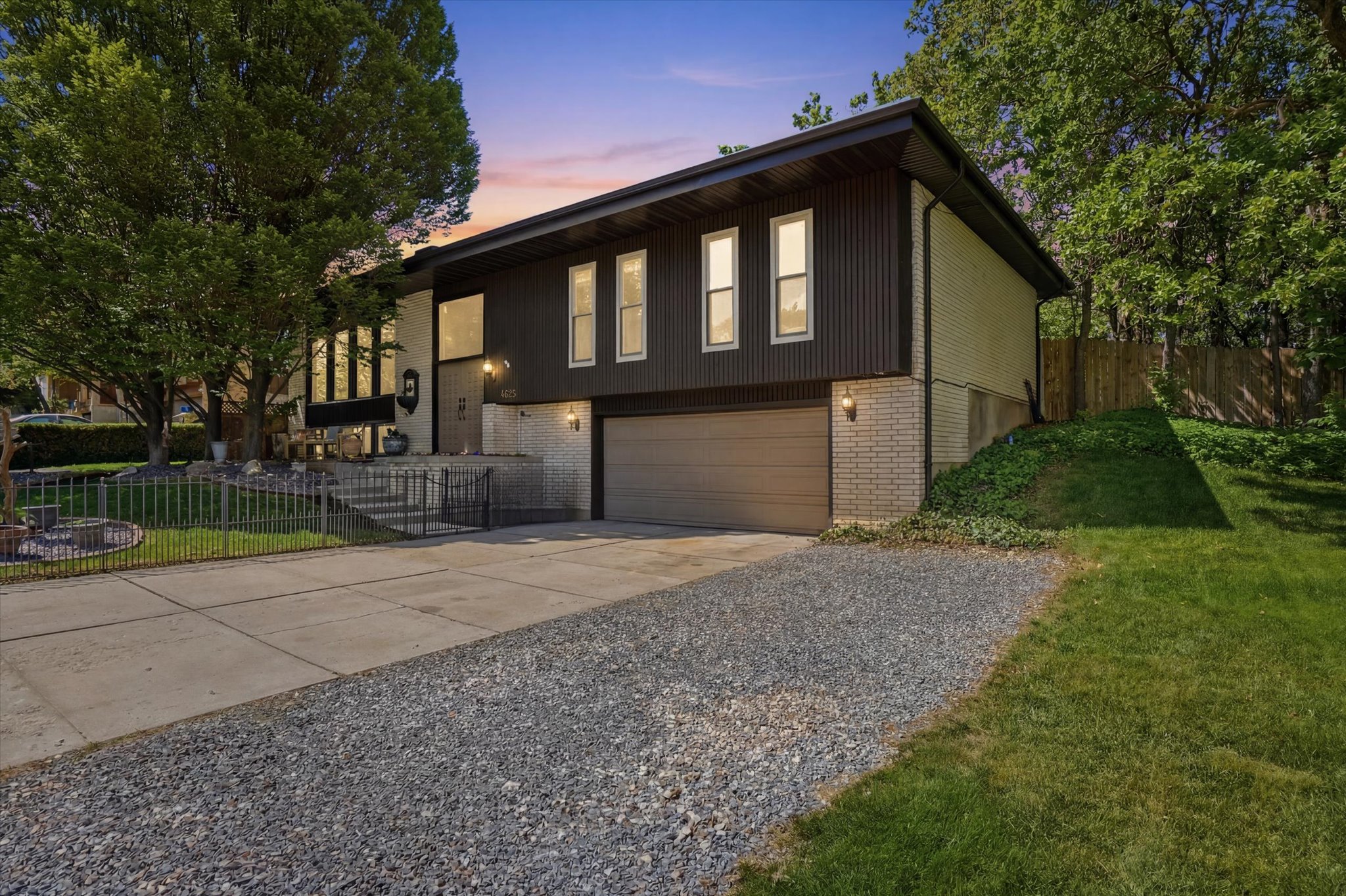Split-level residence featuring a dark corrugated metal siding and light brick exterior