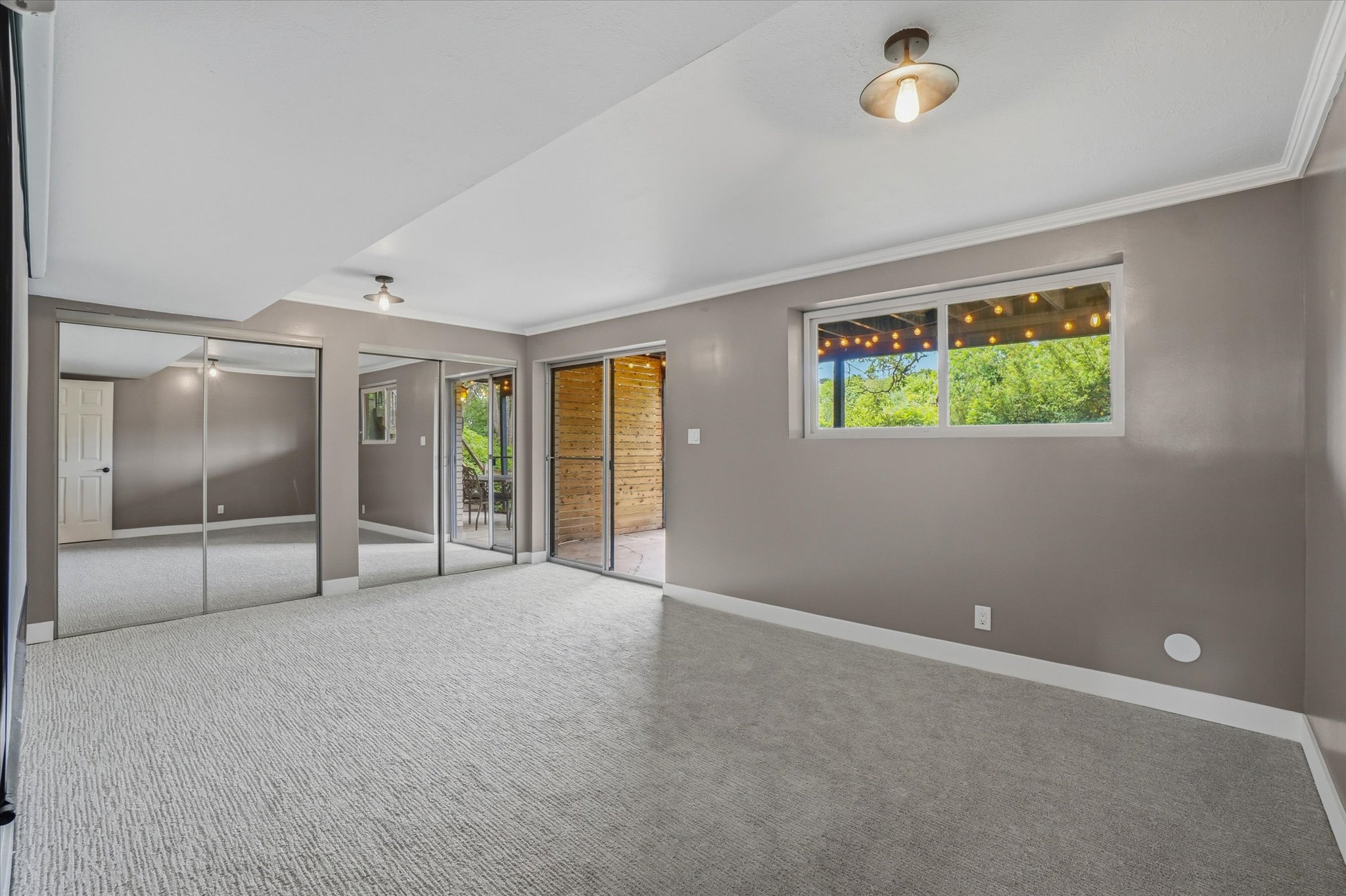 Spacious room featuring light gray textured carpet and neutral wall paint