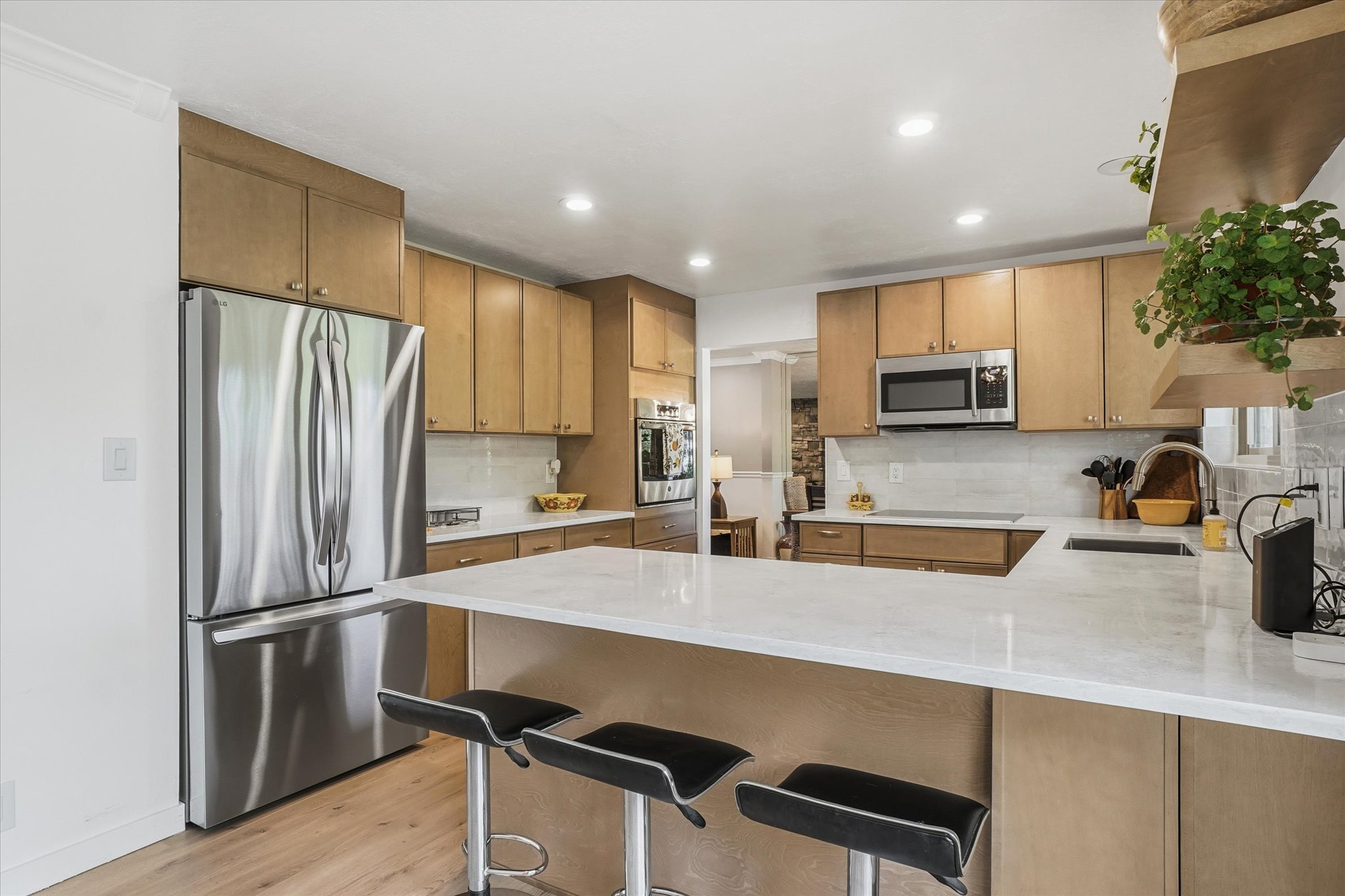 Kitchen featuring light wood-finish cabinetry, stainless steel appliances, white countertops, a tiled backsplash, and recessed lighting