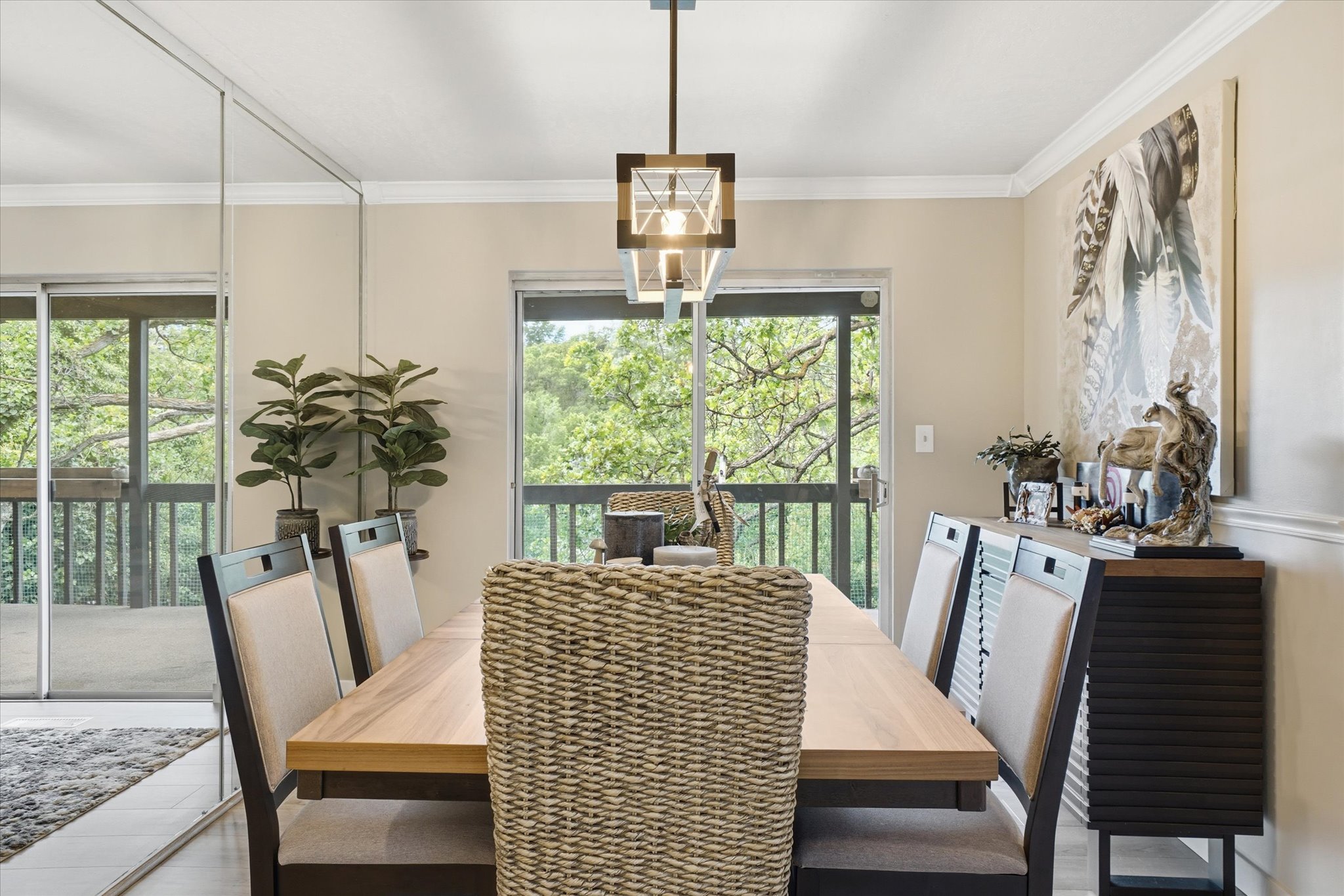 Dining area featuring a contemporary chandelier, two sliding glass doors, and a wood-finish dining table