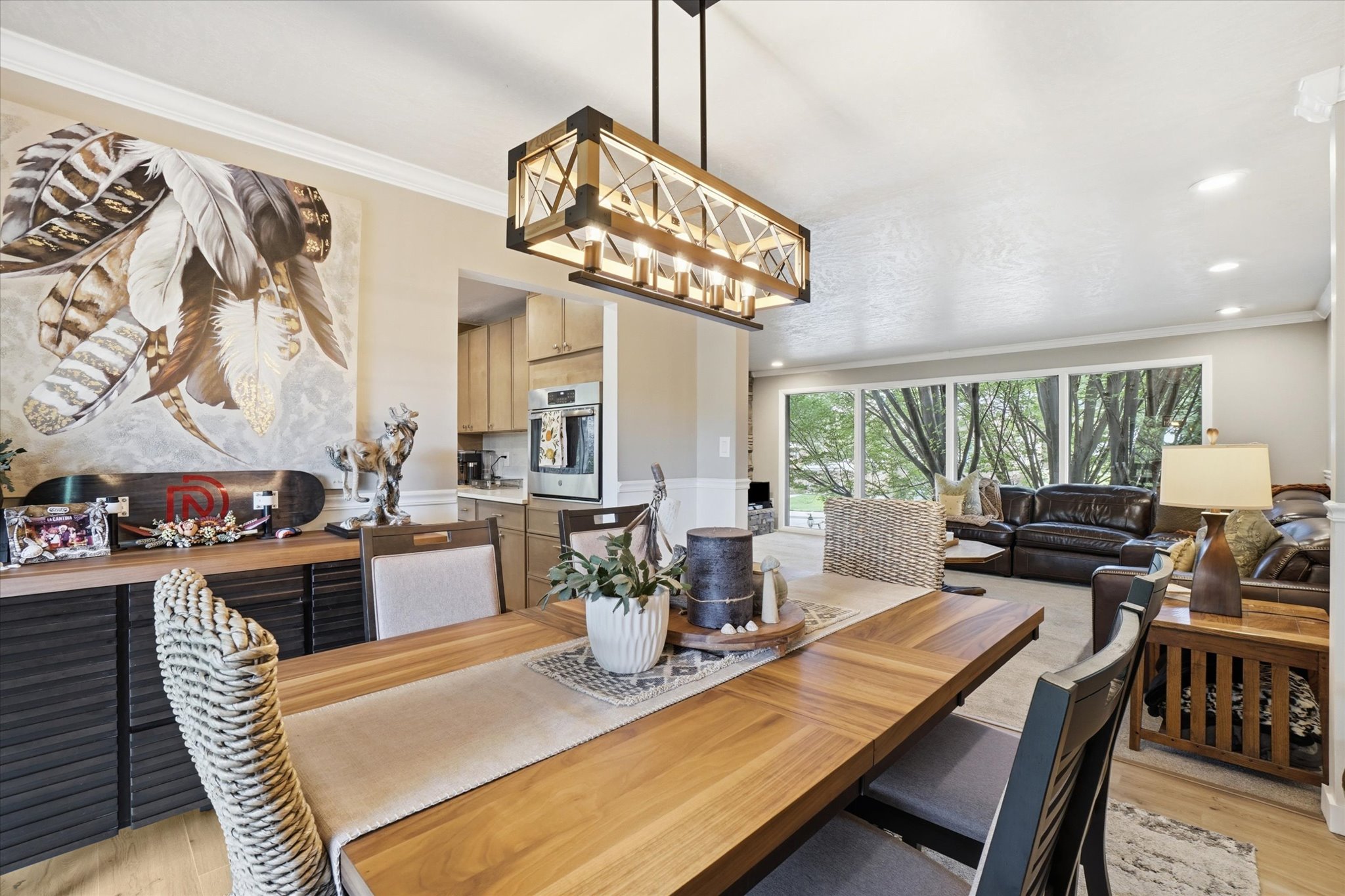 Open-concept dining area featuring a wood-finish dining table and a linear chandelier with exposed bulbs