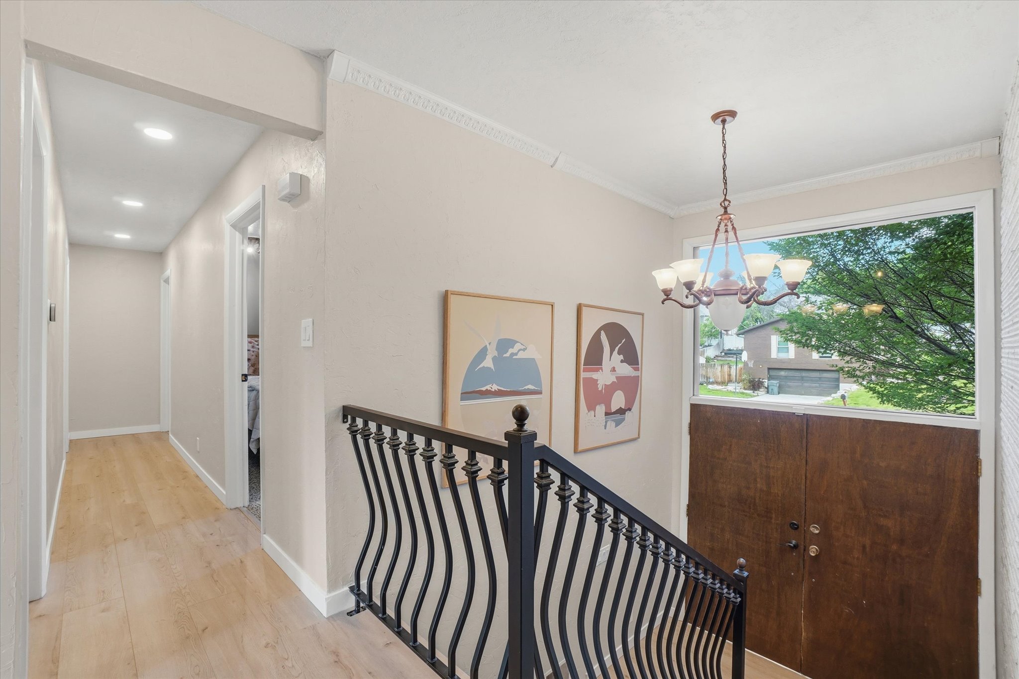 Entryway featuring a decorative iron railing, a warm wood-finish door, and an overhead chandelier