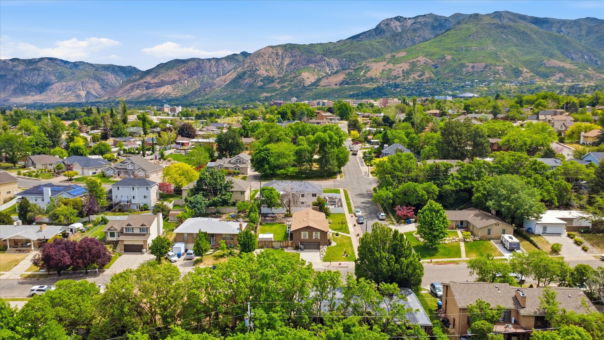 Residential neighborhood featuring a variety of architectural styles, mature trees, and mountainous terrain in the background