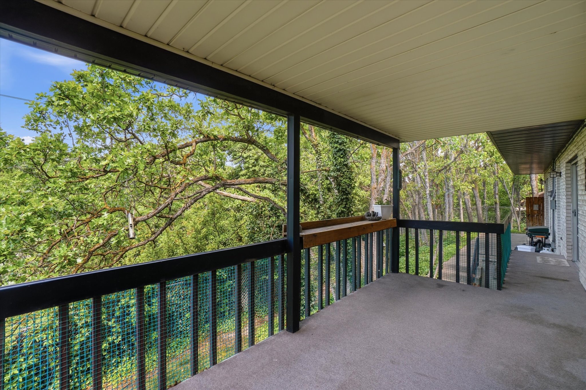 Covered outdoor patio with a textured concrete surface and dark railing