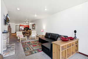 Open-concept living space featuring a stone fireplace, wall-mounted television, and recessed lighting