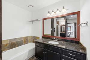 Bathroom featuring a dark wood-finish vanity with a single sink, dark countertop, and a large mirror with a wood-finish frame