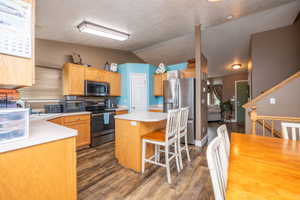 Kitchen featuring light wood cabinetry, white countertops, stainless steel appliances, and wood-finish flooring