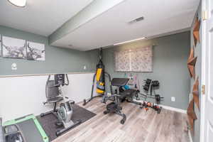 Versatile finished room featuring wood-finish flooring, a window with blinds, recessed lighting, and a two-tone wall treatment with wainscoting