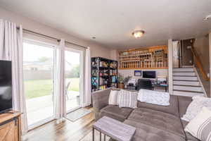 Spacious living area featuring wood-finish flooring, sliding glass patio doors, and a staircase with a wood railing