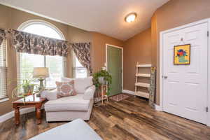 Interior entry area featuring wood-finish flooring, a vaulted ceiling, and a prominent arched window with blinds