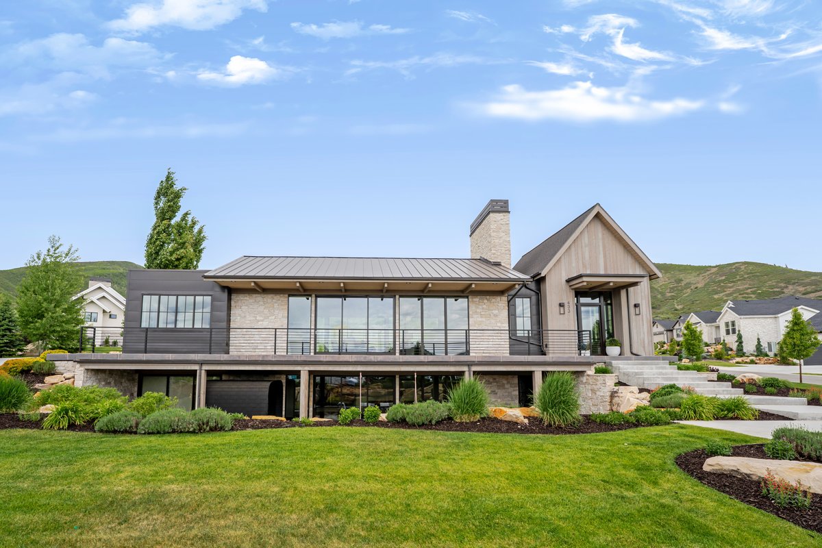 Contemporary exterior featuring stacked stone, vertical wood-finish siding, and dark metal accents