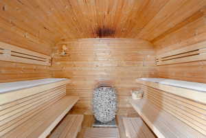 Interior sauna featuring tongue-and-groove wood paneling, multi-tiered wood benches, and a central rock heater