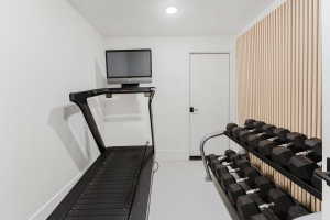 Dedicated fitness space featuring clean white walls, recessed lighting, and a modern slat wall accent