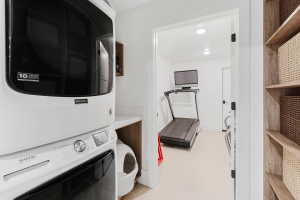 Dedicated laundry area featuring a stacked Maytag washer and dryer, white countertop space, and wood-finish cabinetry