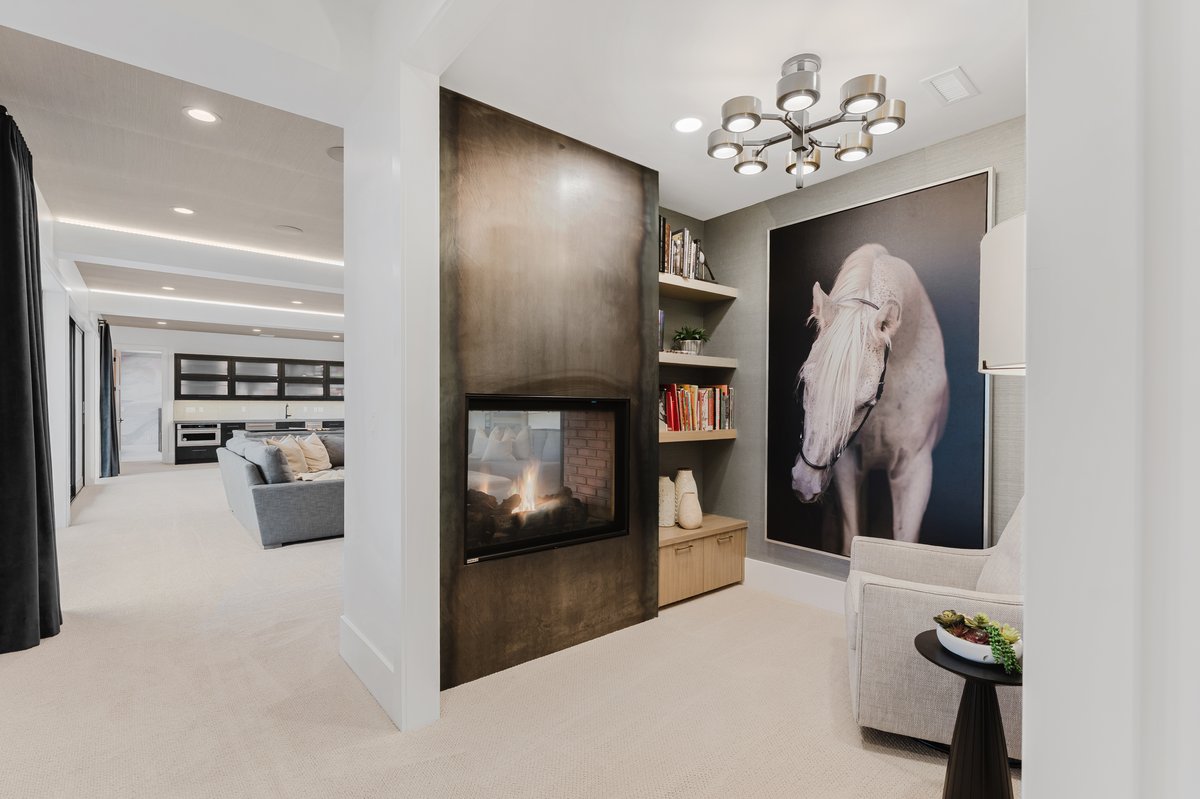 Contemporary fireplace with a dark metal surround, integrated shelving, an overhead light fixture, and plush carpeting