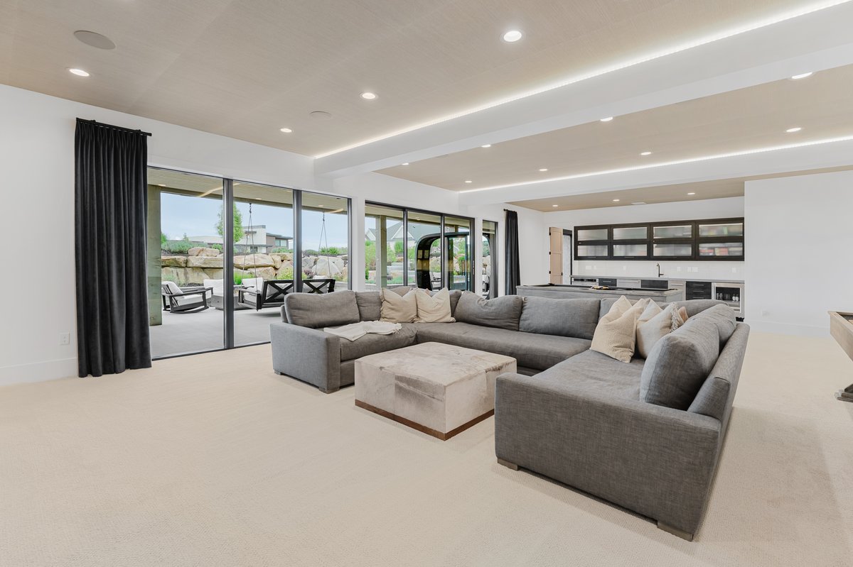 Open-concept entertainment space featuring recessed lighting, a built-in wet bar with cabinetry, and large sliding glass doors leading to an outdoor patio with rock landscaping