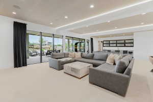Open-concept entertainment space featuring recessed lighting, a built-in wet bar with cabinetry, and large sliding glass doors leading to an outdoor patio with rock landscaping