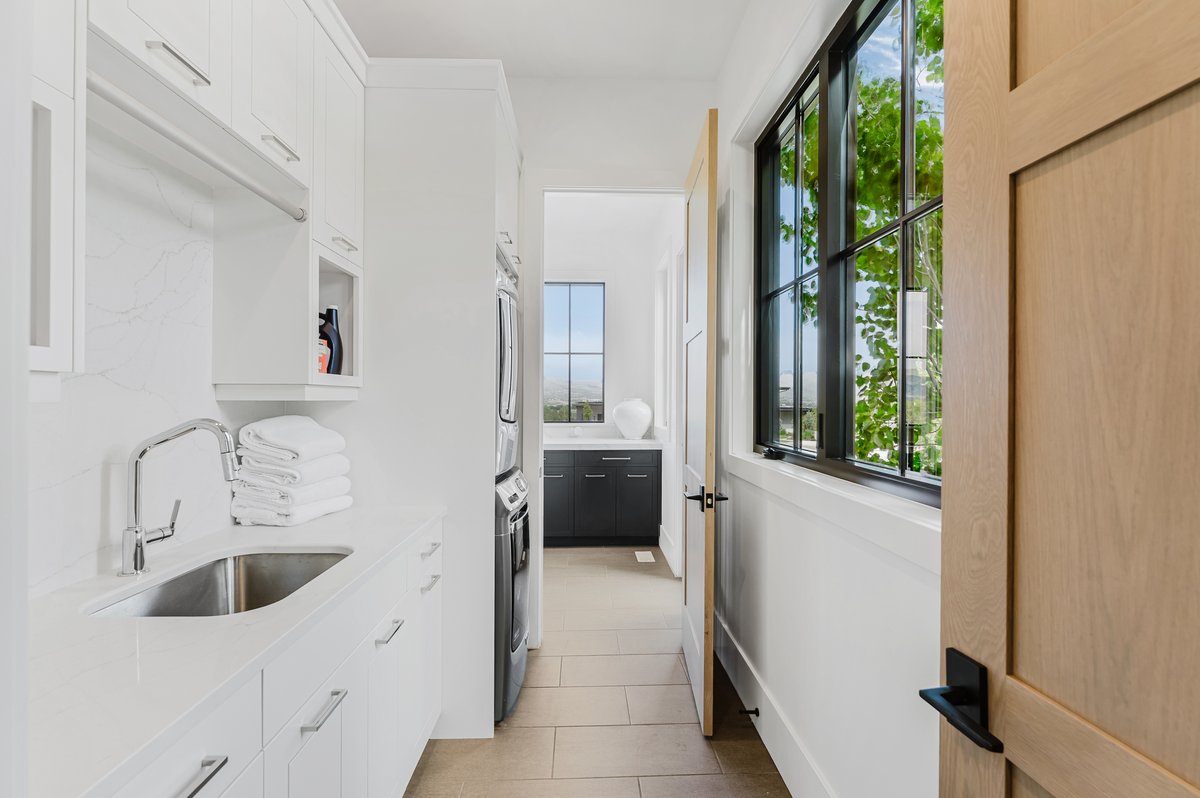 Laundry area featuring white cabinetry, a single basin sink with a chrome faucet, and a light-colored countertop