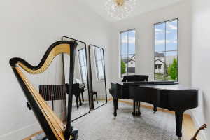High ceilings featuring a contemporary chandelier, two tall windows with grid patterns, and light wood-finish flooring