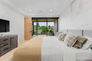 Recessed lighting illuminating a spacious room with a light wood-finish door and a large glass sliding door opening to an outdoor patio with stone steps and landscaping