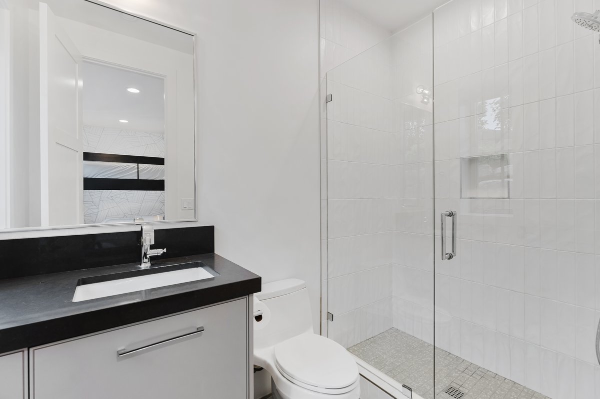 Full bathroom featuring a frameless glass shower enclosure, a recessed shower niche, and mosaic tile shower flooring
