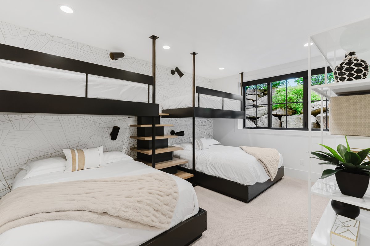 Modern bedroom featuring custom black metal bunk beds with wood-finish steps, recessed lighting, and patterned accent wall