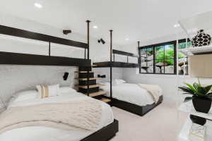 Modern bedroom featuring custom black metal bunk beds with wood-finish steps, recessed lighting, and patterned accent wall