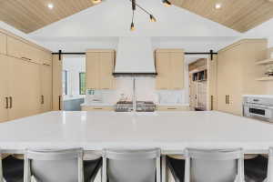 Spacious kitchen featuring a large white countertop island, integrated stainless steel appliances, and abundant light wood-finish cabinetry