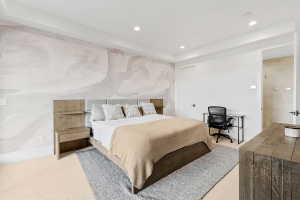 Recessed lighting illuminates a space featuring a decorative accent wall and light-toned carpeting