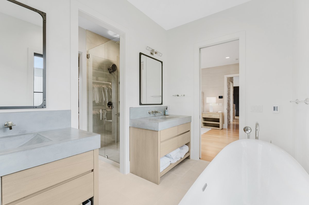 Bright bathroom featuring dual wood-finish vanities with integrated concrete sinks
