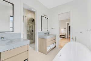 Bright bathroom featuring dual wood-finish vanities with integrated concrete sinks