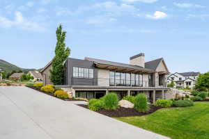 Modern architectural residence featuring extensive glazing, a stone facade, and dark horizontal siding