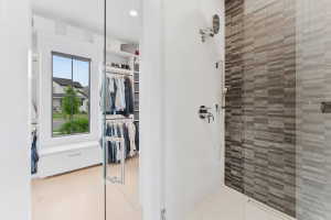 Spacious walk-in closet with custom built-in shelving, wood-finish flooring, and natural light from a large window
