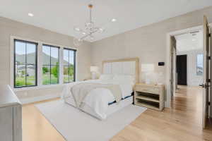 Bedroom featuring multiple black-framed windows, hardwood flooring, and a modern chandelier