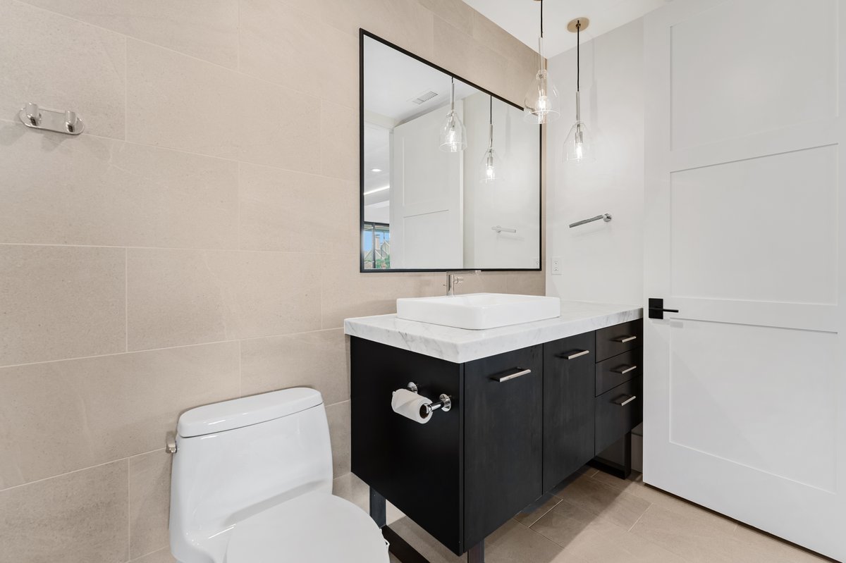 Modern bathroom featuring a dark wood-finish vanity with a white countertop and rectangular vessel sink