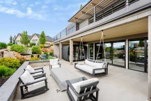 Expansive outdoor patio featuring a concrete surface, a ceiling-mounted swing bed, and a series of floor-to-ceiling glass sliding doors
