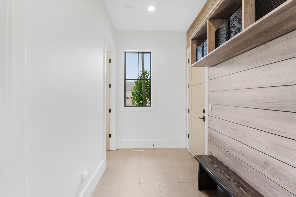 Entryway featuring a built-in bench, overhead shelving, and wood-finish accent wall