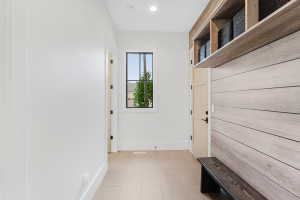 Entryway featuring a built-in bench, overhead shelving, and wood-finish accent wall