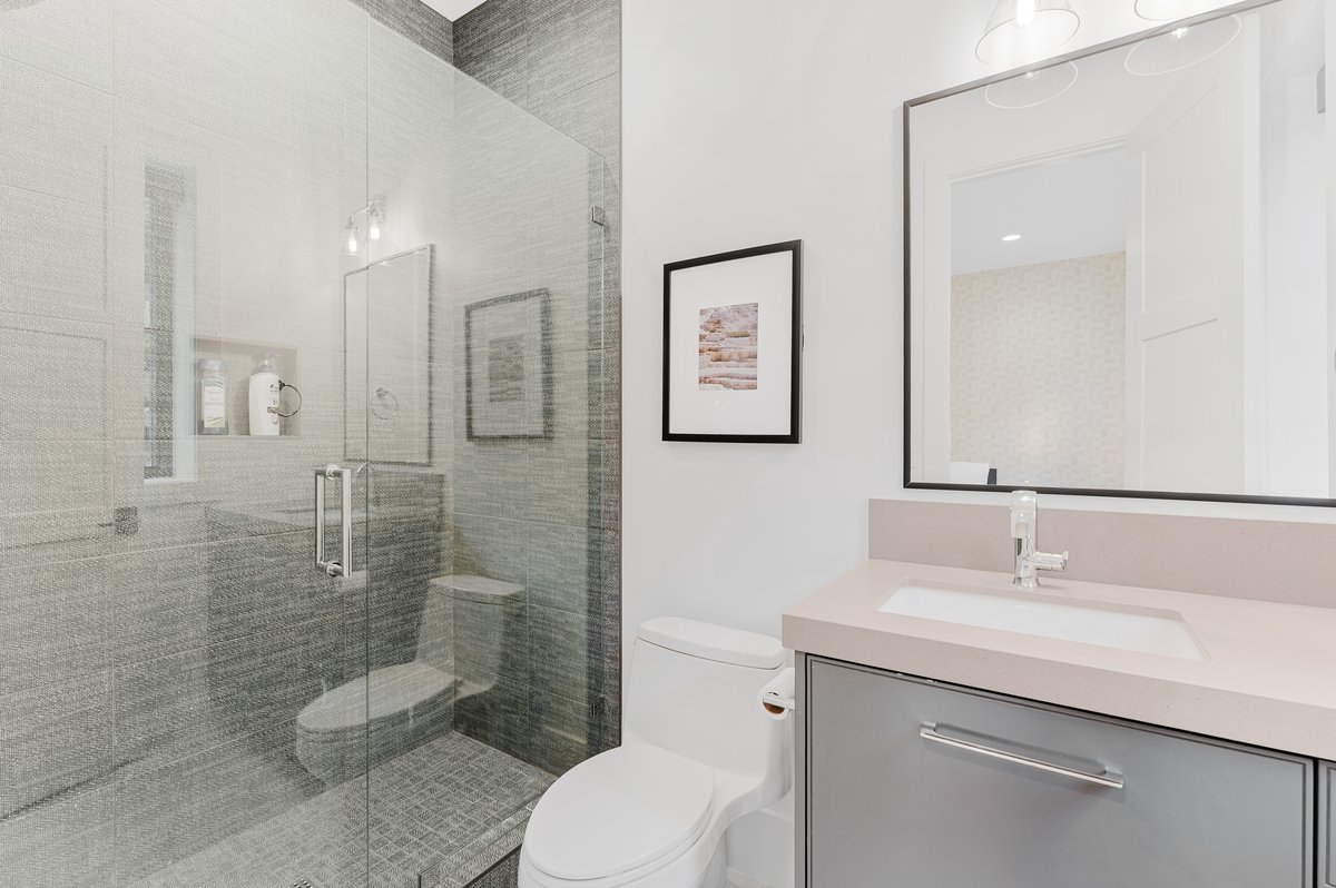 Glass-enclosed shower with gray tiled walls and floor, featuring a built-in shower niche