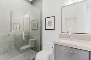 Glass-enclosed shower with gray tiled walls and floor, featuring a built-in shower niche