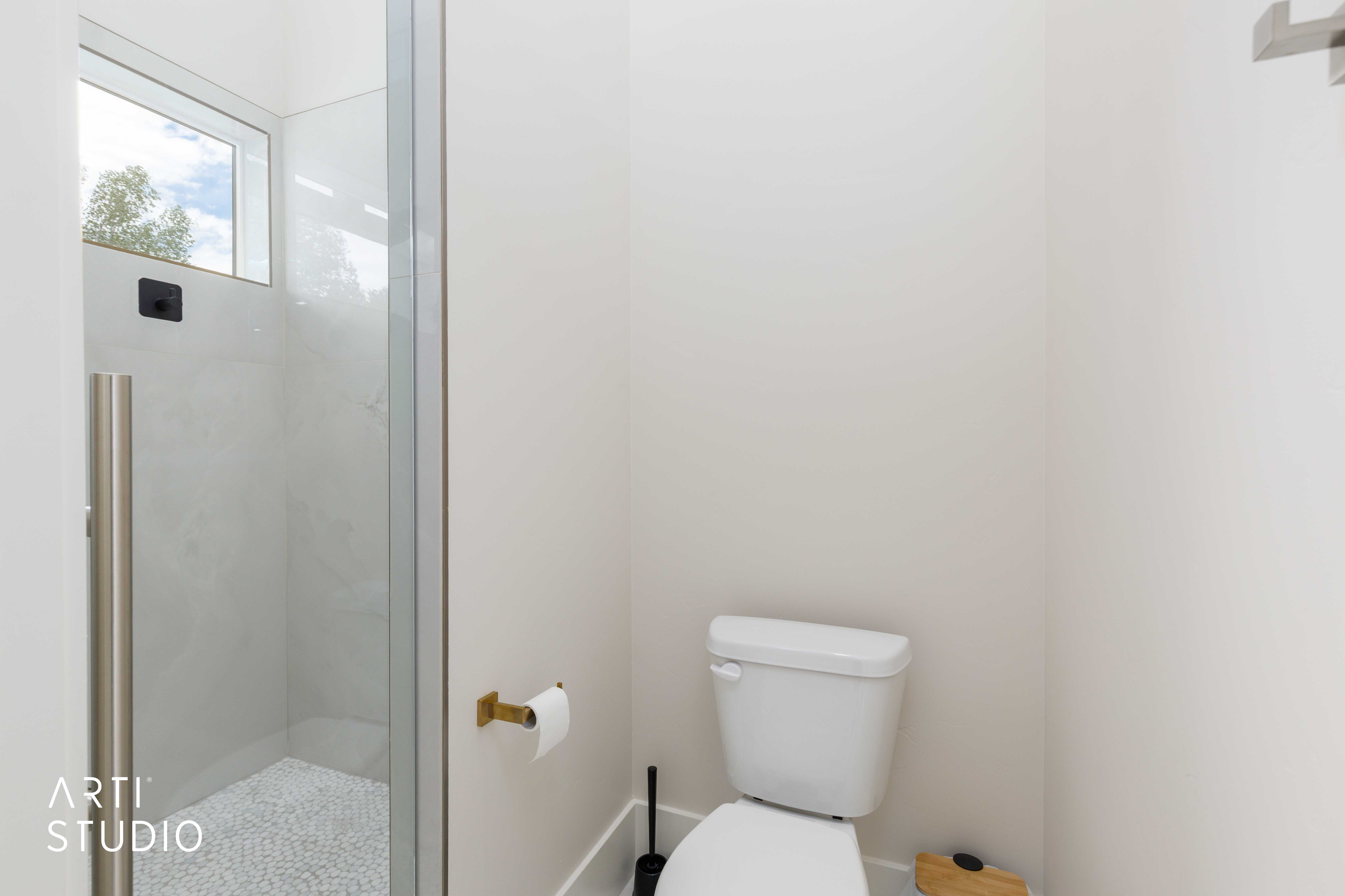 Contemporary shower enclosure featuring clear glass panels, a full-height window, and a pebble-tiled floor