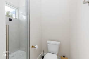 Contemporary shower enclosure featuring clear glass panels, a full-height window, and a pebble-tiled floor