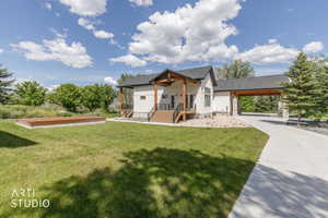 Modern farmhouse exterior featuring white vertical siding, a dark pitched roof, wood-finish columns, a covered front porch with wood-finish steps, and a concrete driveway leading to a covered carport with stone pillar supports