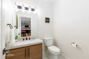 Vanity featuring a stone-finish countertop, undermount sink, and wood-finish cabinetry with black and gold-tone hardware