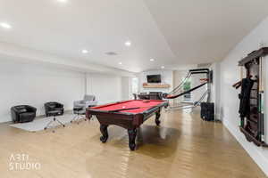 Spacious entertainment room featuring light wood-finish flooring, recessed lighting, and white walls