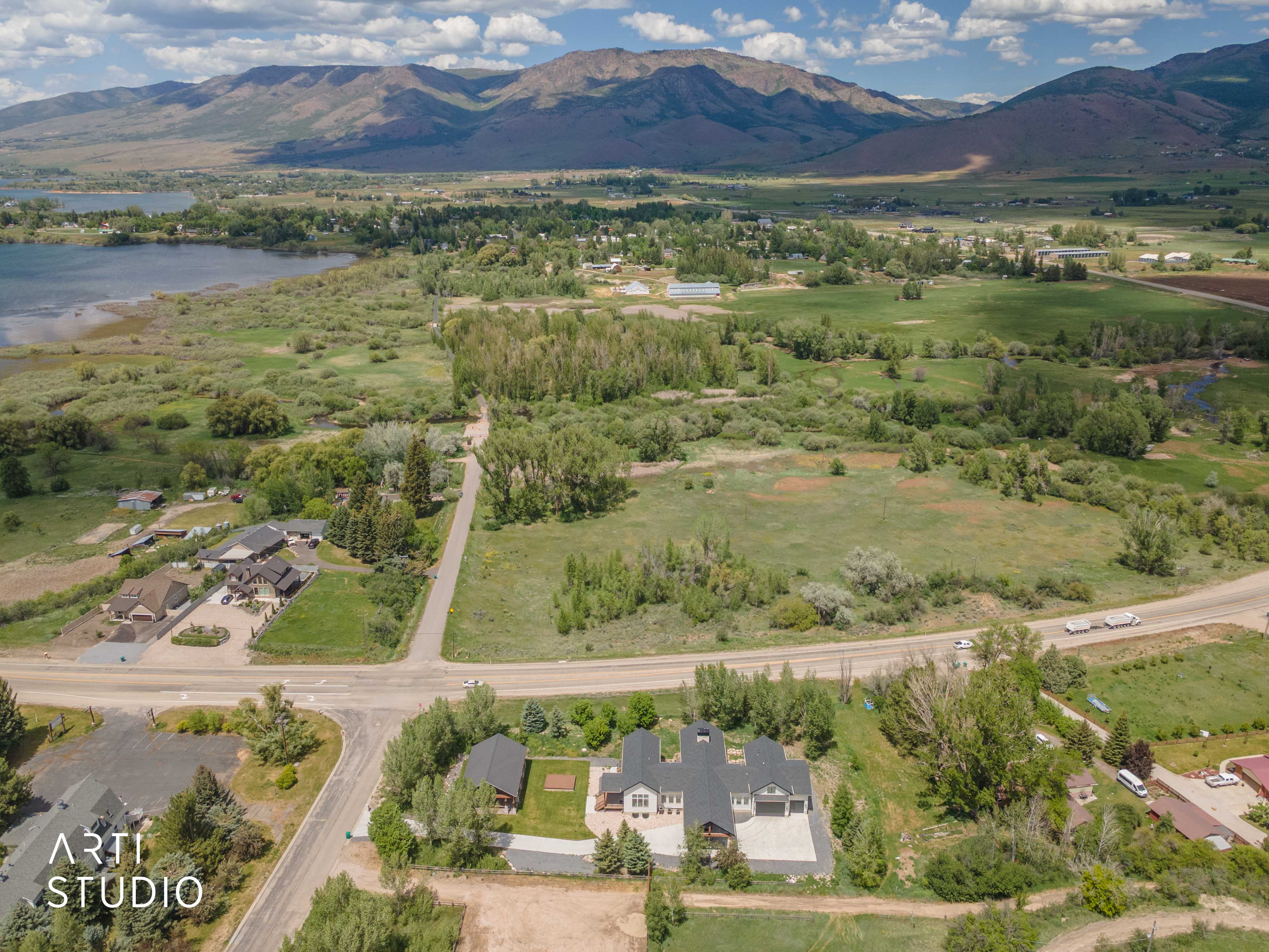 Aerial perspective showcasing a sprawling landscape with a prominent body of water, distant mountains, and extensive green fields