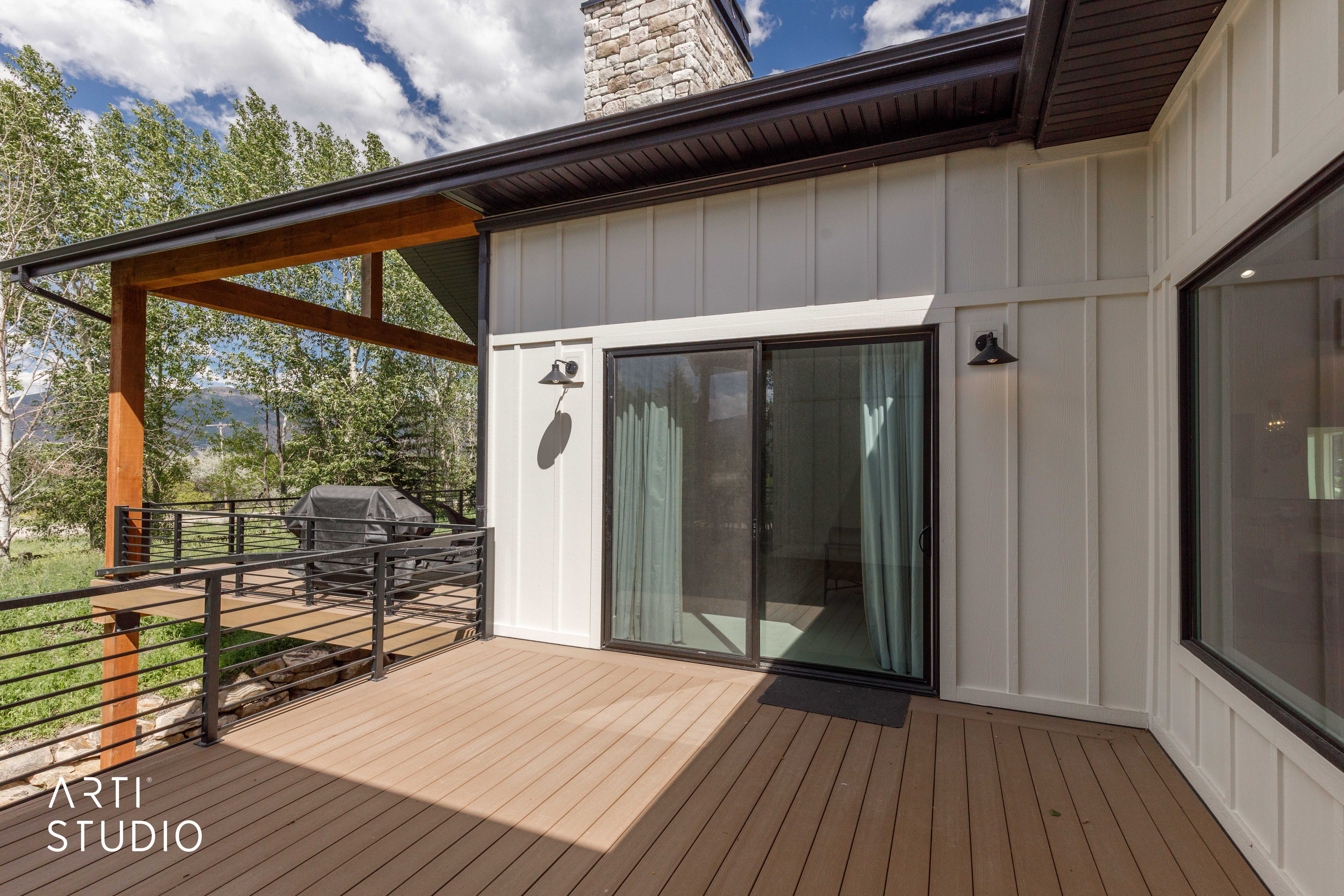 Expansive deck featuring composite wood-finish flooring, black metal railings, and a covered section with wood beams