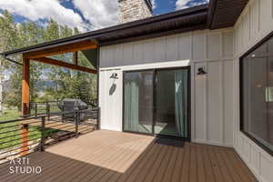 Expansive deck featuring composite wood-finish flooring, black metal railings, and a covered section with wood beams