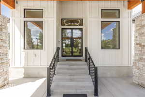 Modern entry featuring board and batten siding, stone veneer accents, and a wood beam overhang